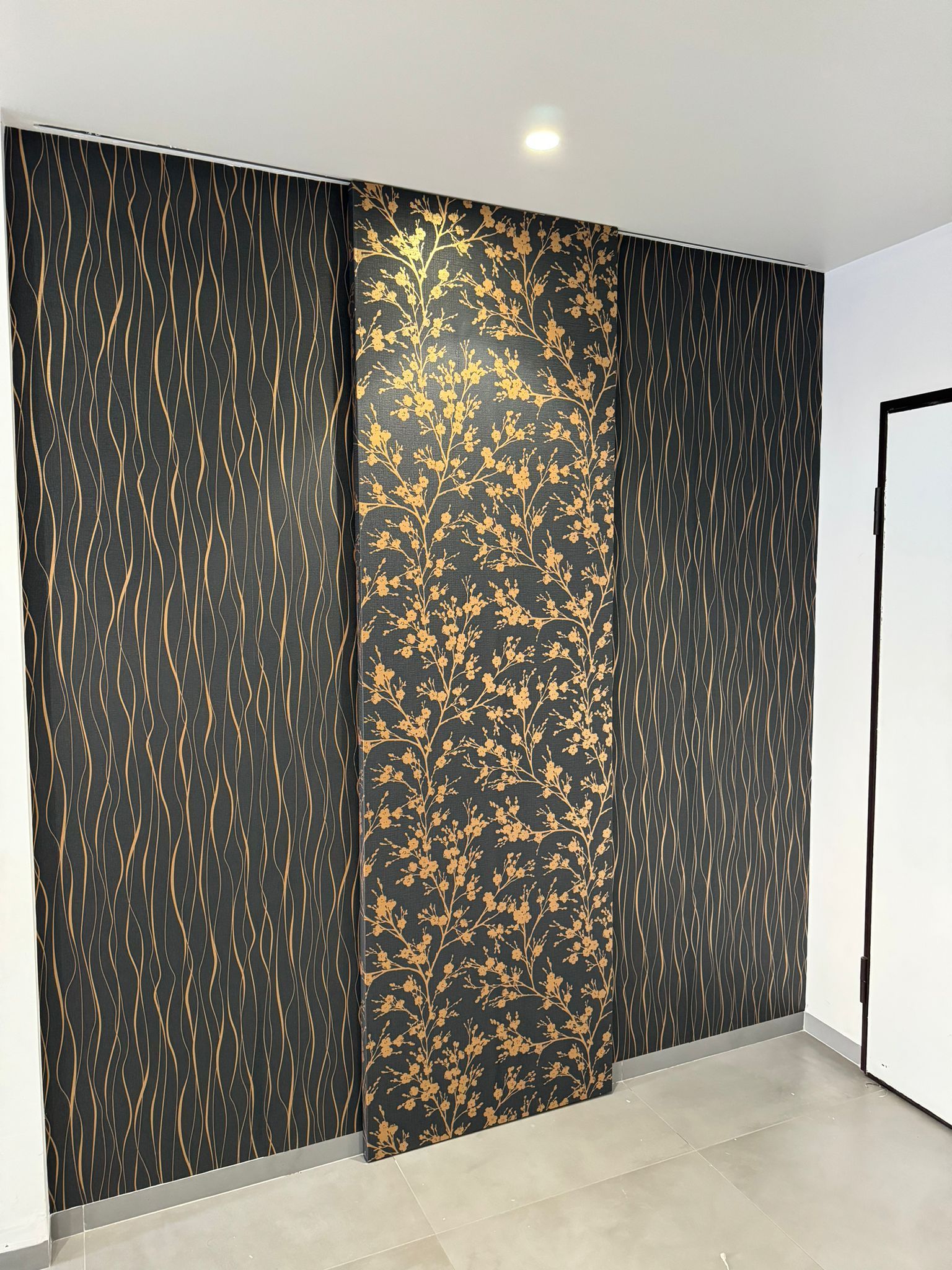 Una stanza con una parete nera e oro e una porta.