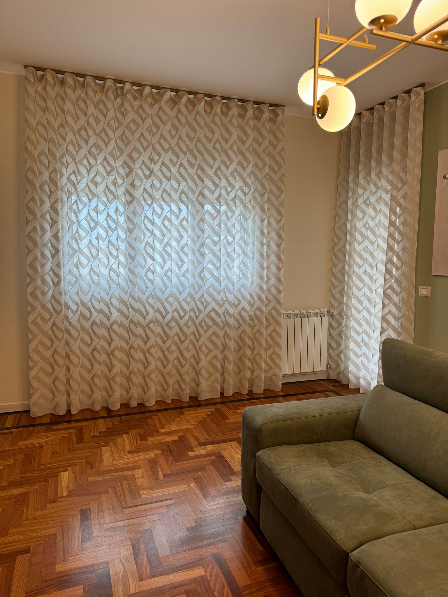 Un soggiorno con un divano e una finestra con le tende.