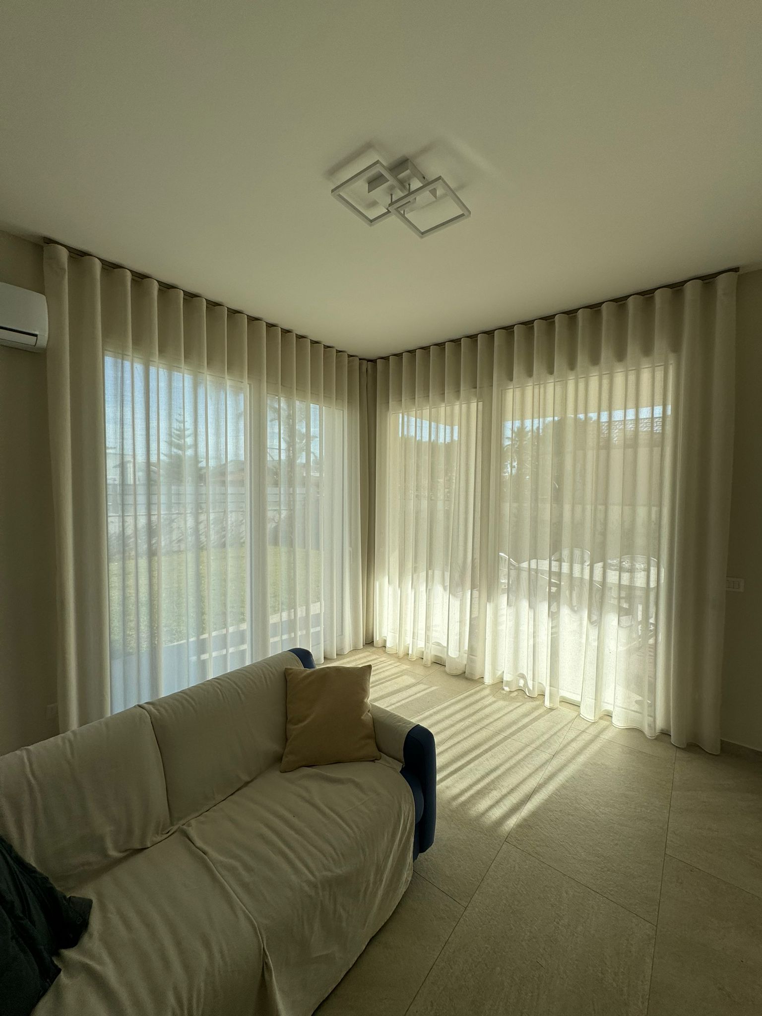 Un soggiorno con un divano, tende e molte finestre.