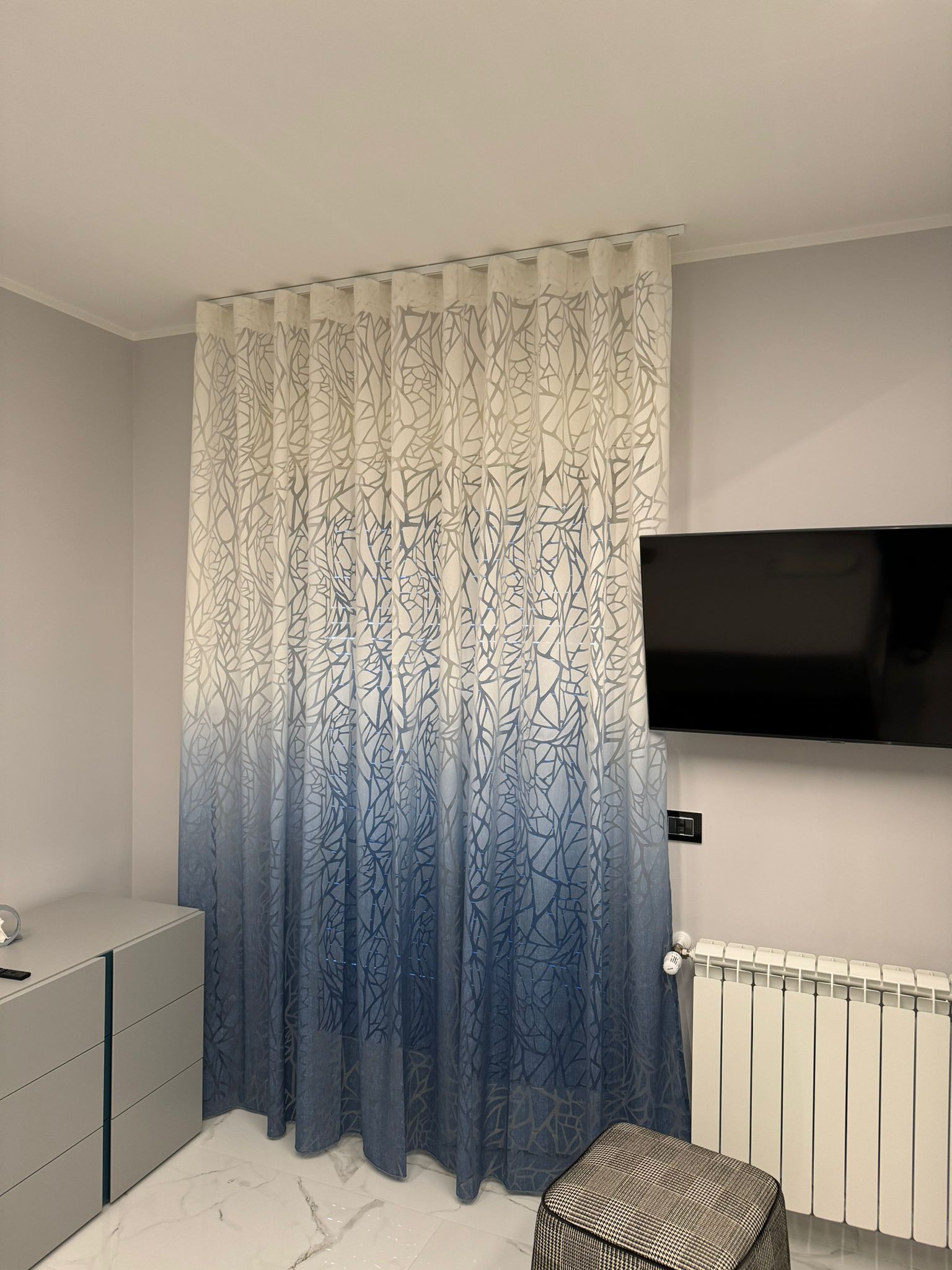 Una camera da letto con una tenda blu e bianca appesa al muro.