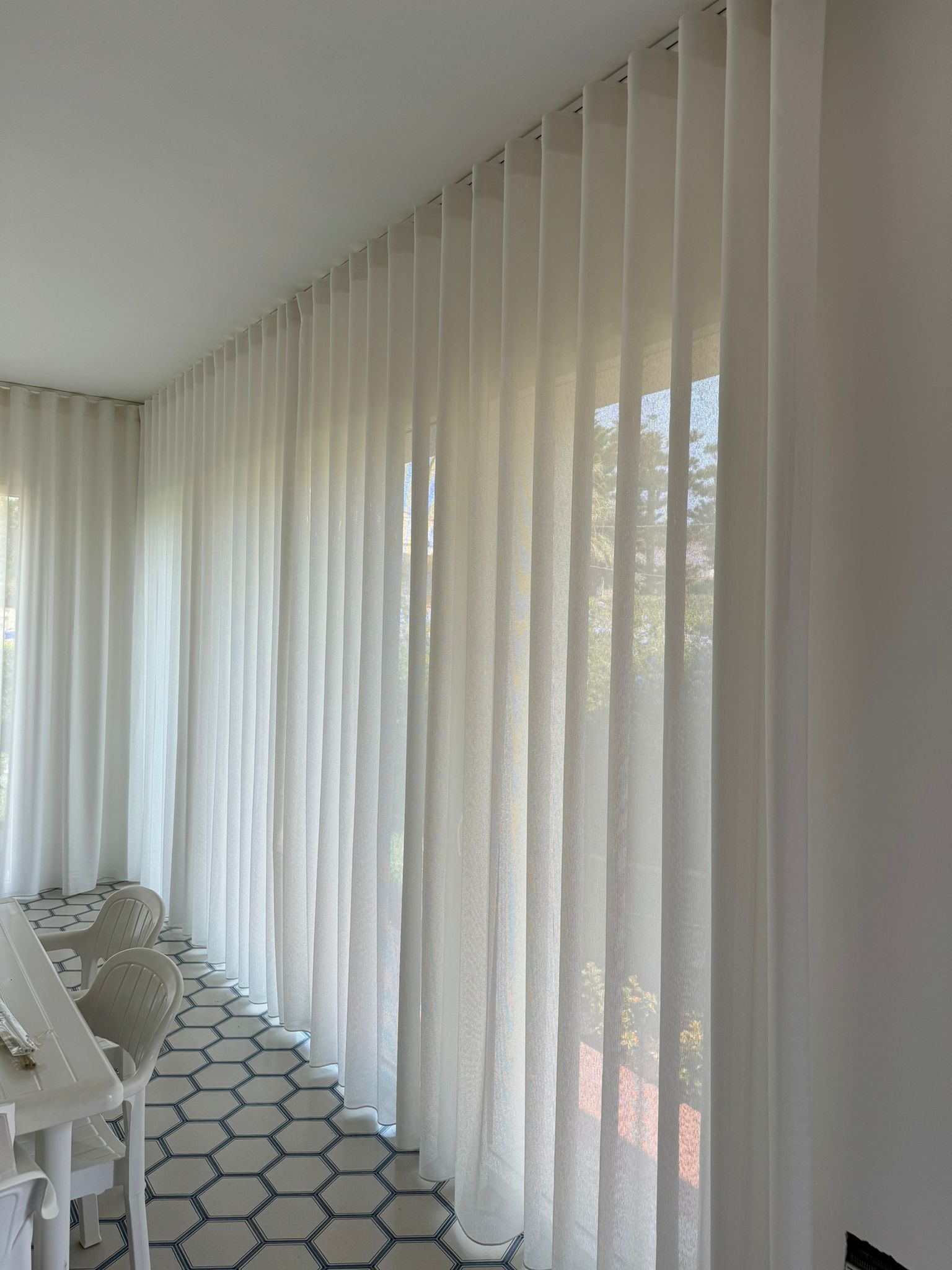 Una stanza con tante tende bianche alle finestre