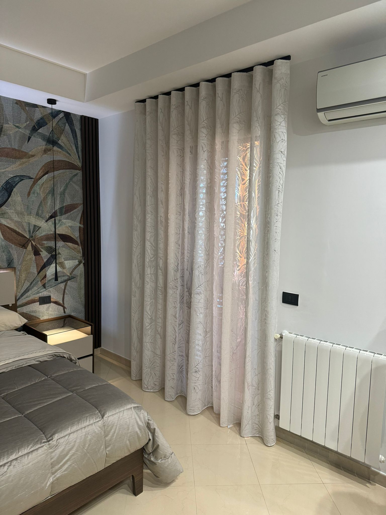 Una camera da letto con un letto, un termosifone e delle tende.