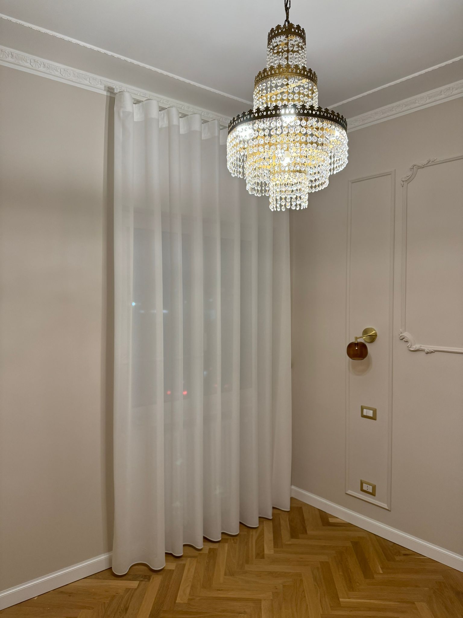 Una stanza con tende bianche e un lampadario appeso al soffitto.