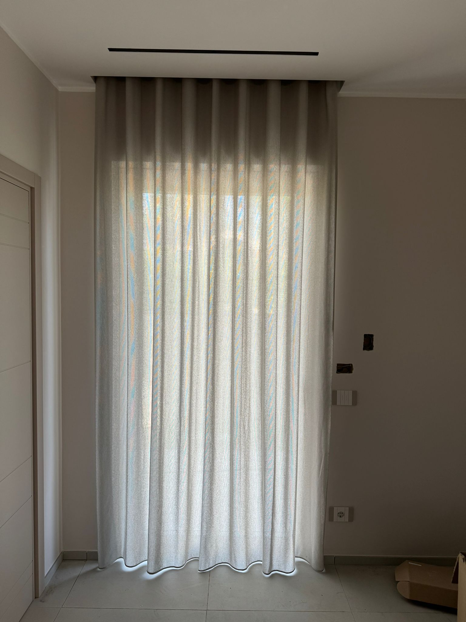 Una tenda bianca è appesa alla finestra di una stanza.