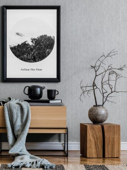 Un soggiorno con un tavolo di legno, un vaso, un quadro sul muro e una coperta.