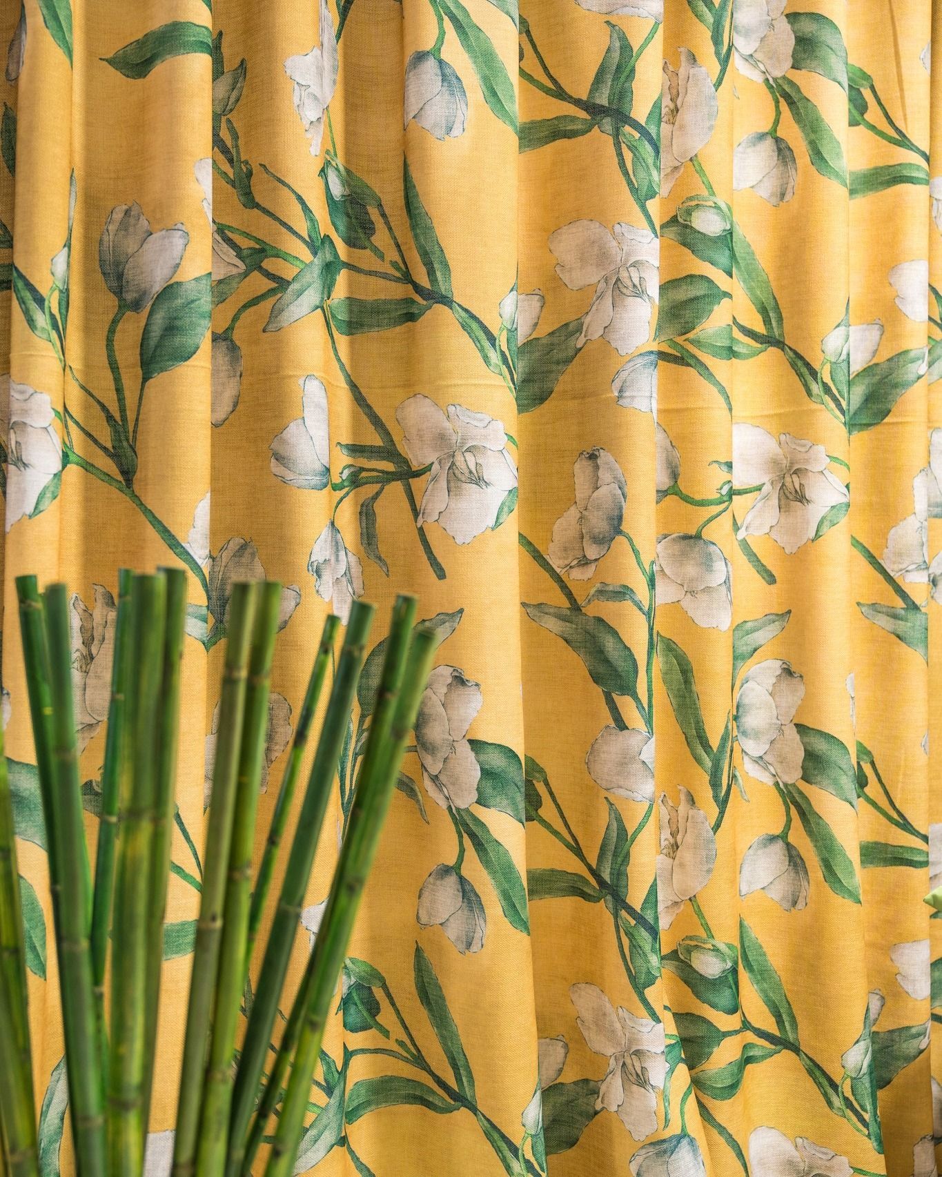 Primo piano di una tenda gialla con fiori bianchi e foglie verdi.