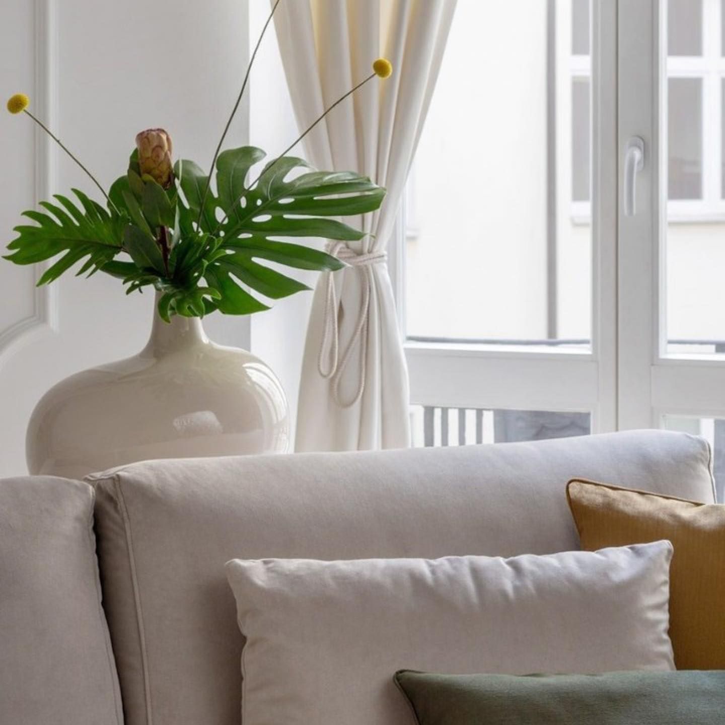 Un vaso di fiori è appoggiato su un divano davanti a una finestra