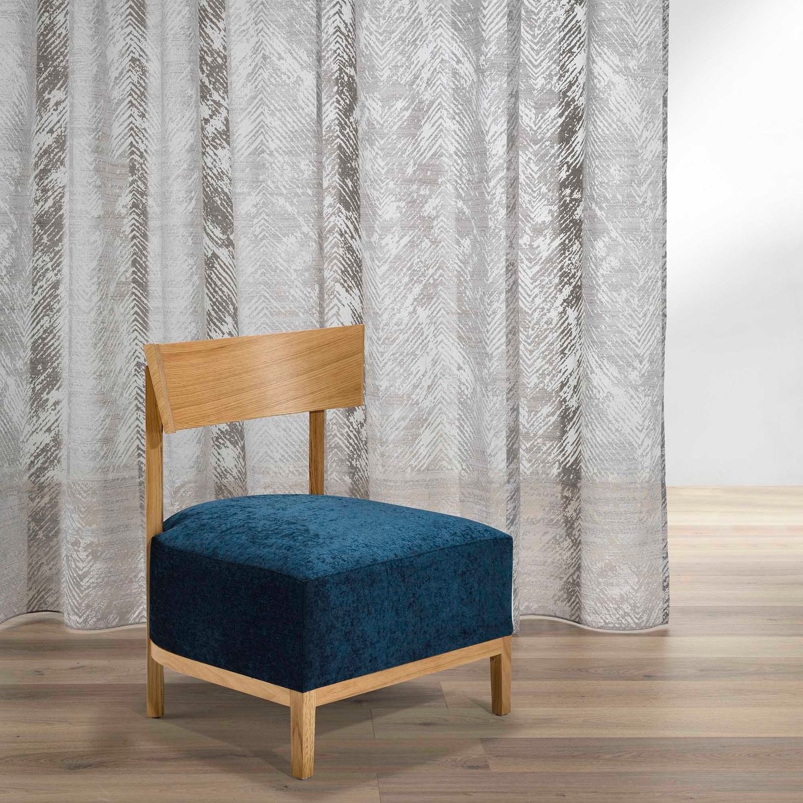 Una sedia blu è seduta davanti a una tenda bianca