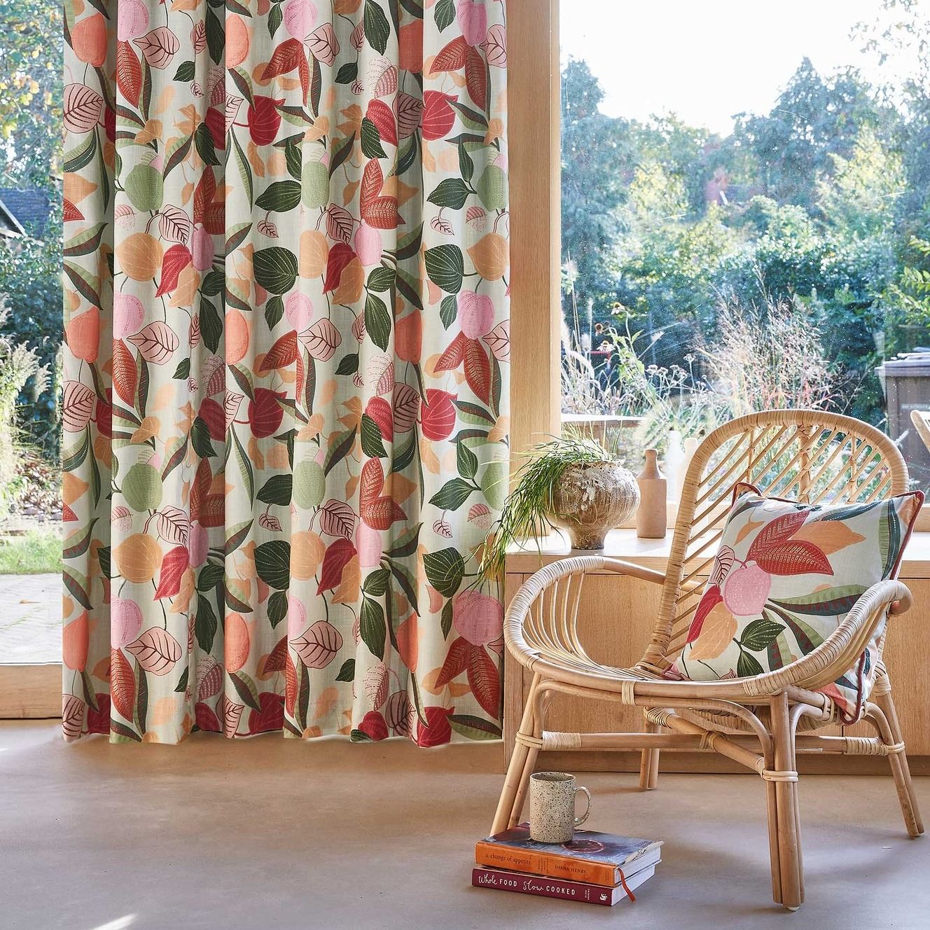 Una sedia di vimini è posta davanti a una finestra con tende floreali.