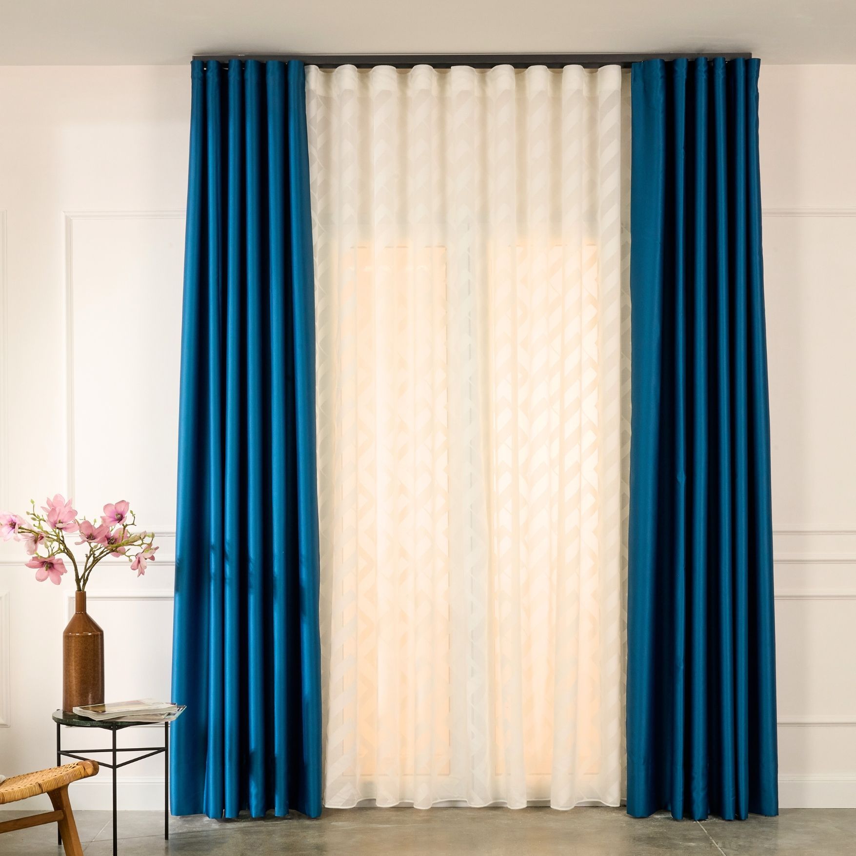 Un soggiorno con tende blu e un vaso di fiori su un tavolo.