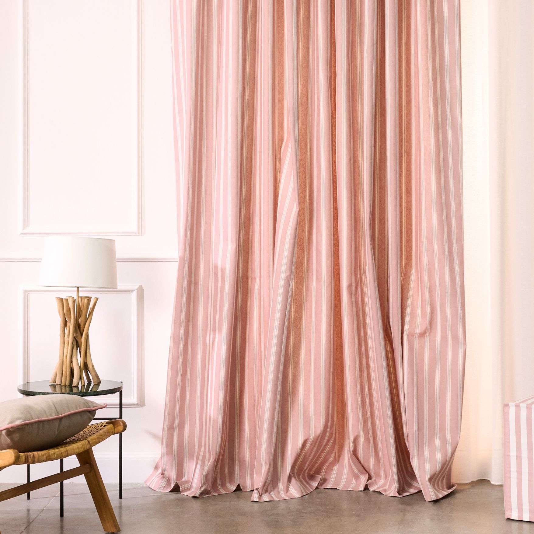 Un soggiorno con tende a righe rosa e bianche e una lampada.