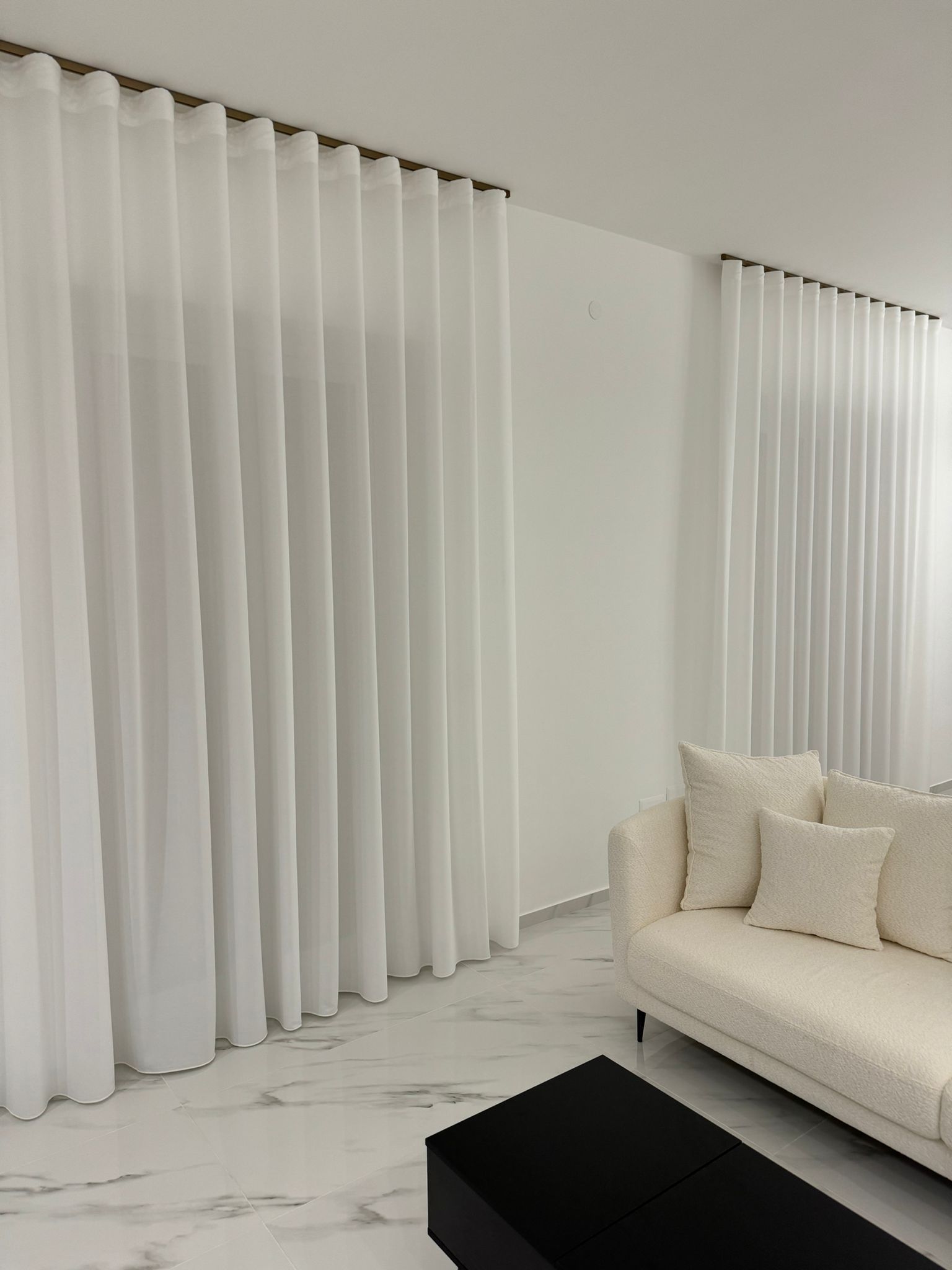 Un soggiorno con tende bianche e un divano bianco