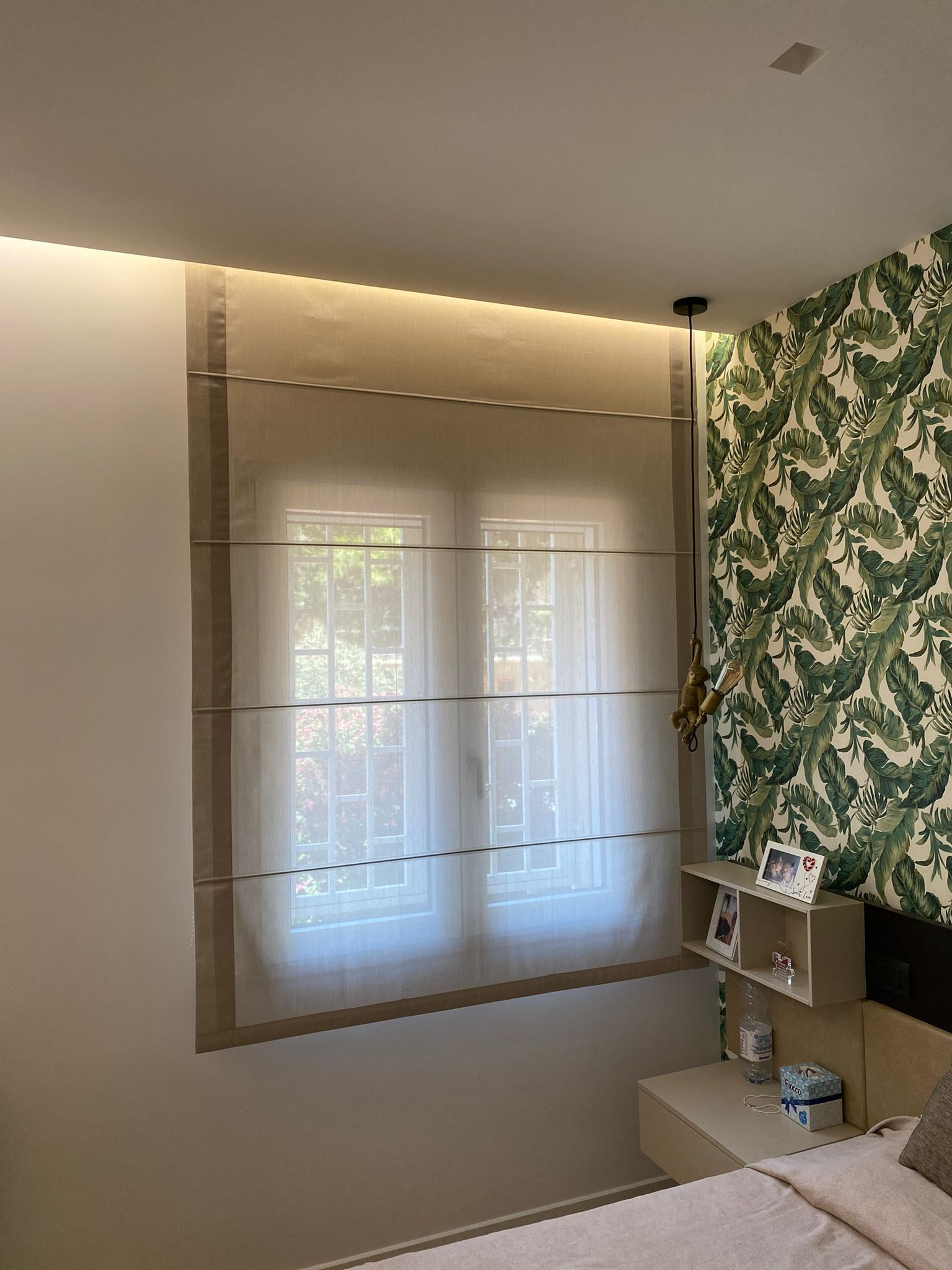 Una camera da letto con un letto e una finestra con tende alla romana.