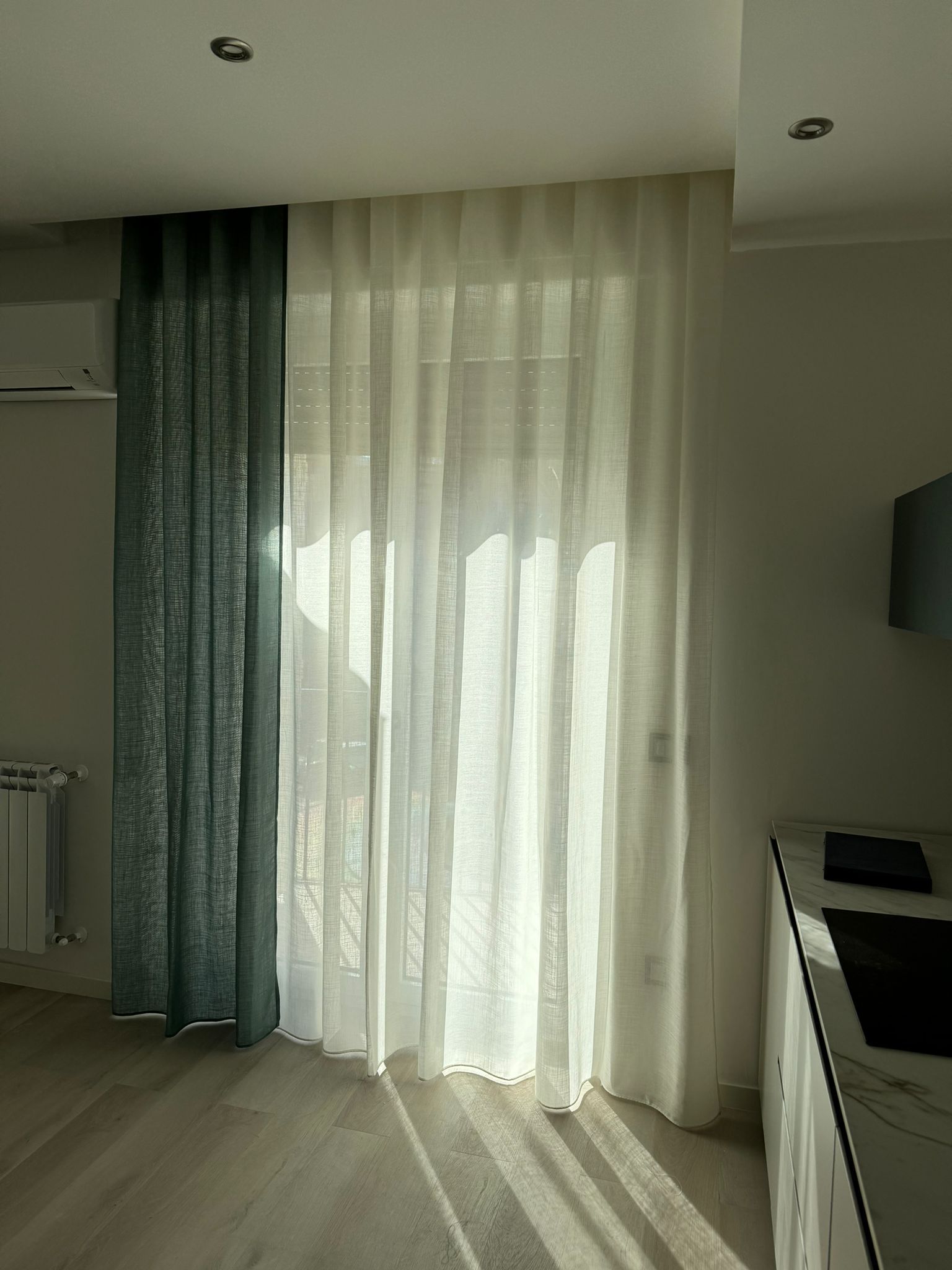 Un soggiorno con una porta scorrevole in vetro e tende bianche.