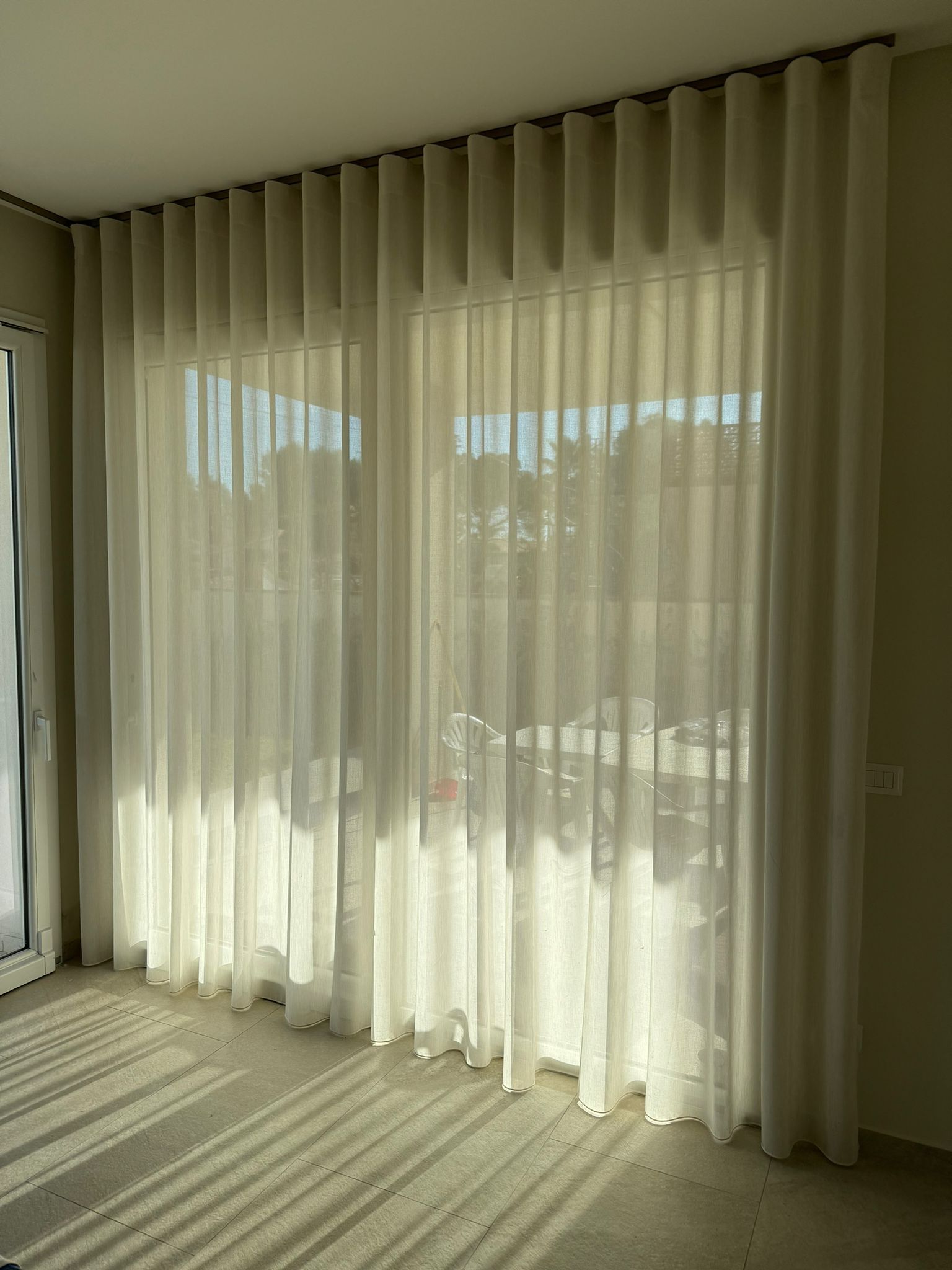 Un soggiorno con una grande finestra e tende bianche.