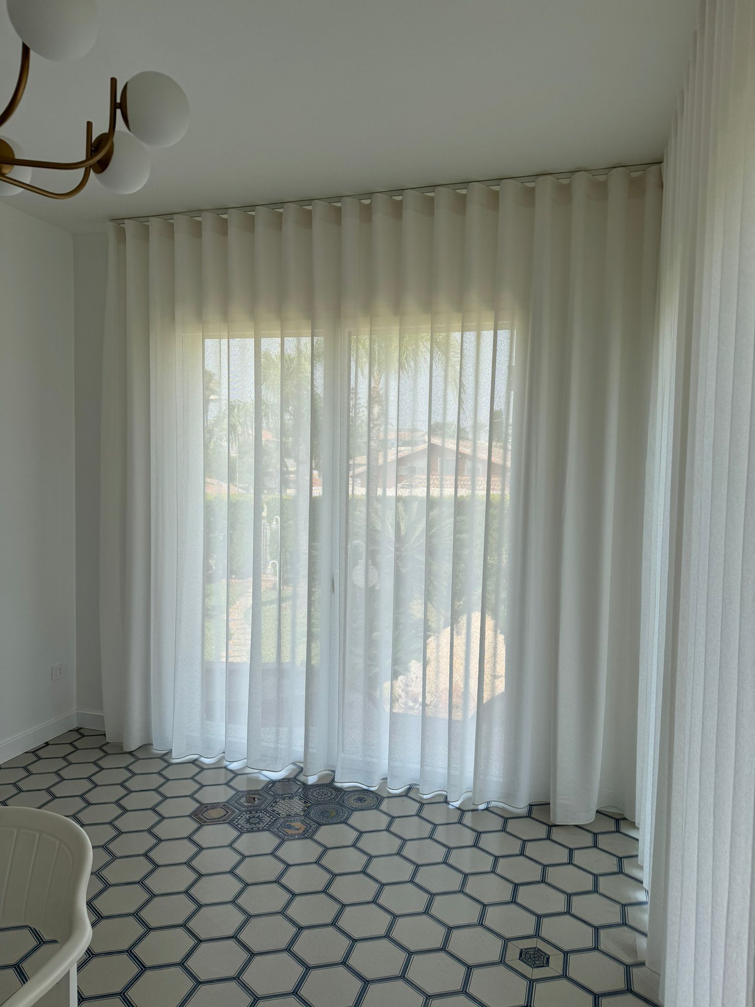 Un soggiorno con tende bianche e un lampadario.