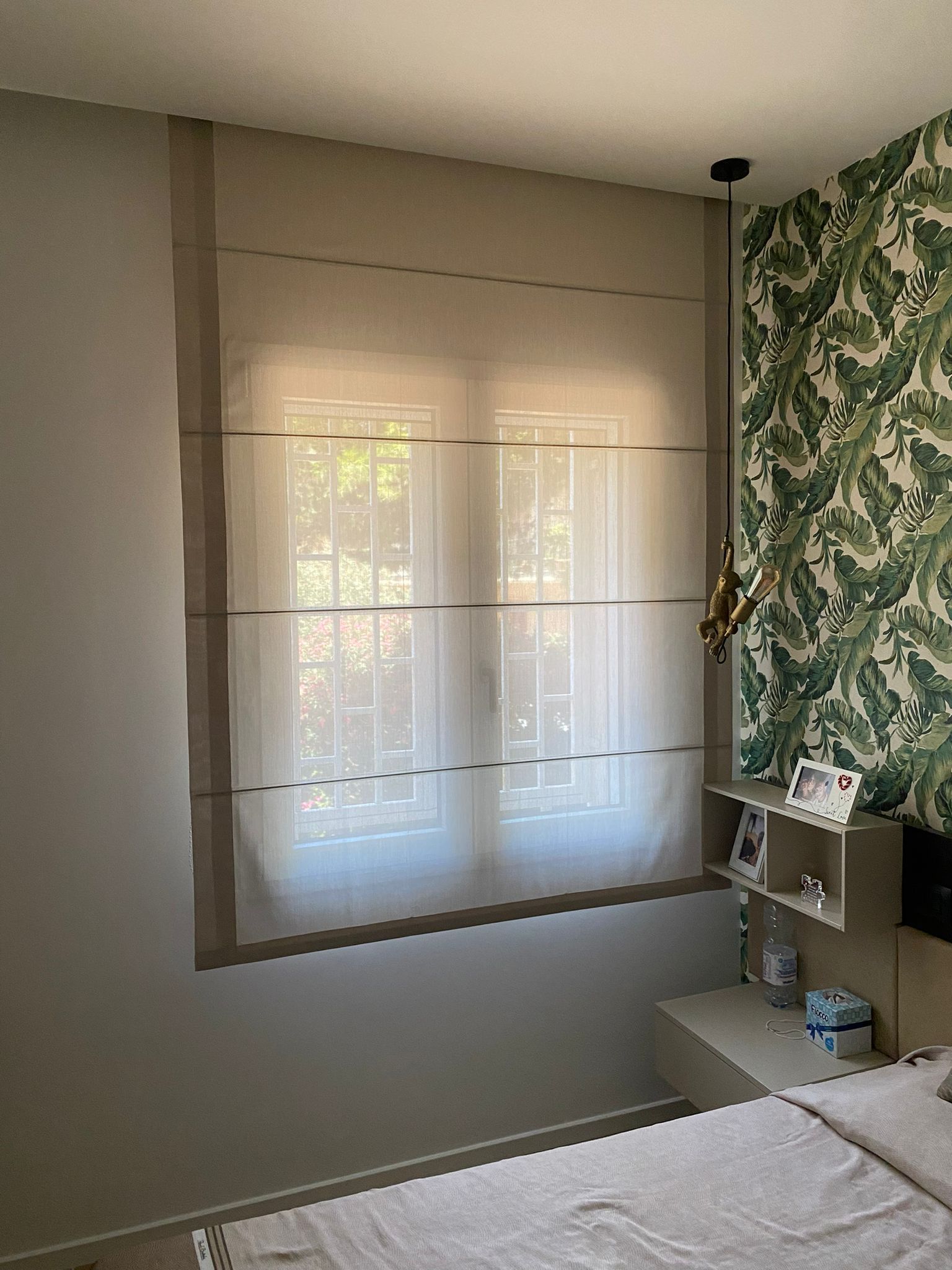 Una camera da letto con un letto e una finestra con tende alla romana.