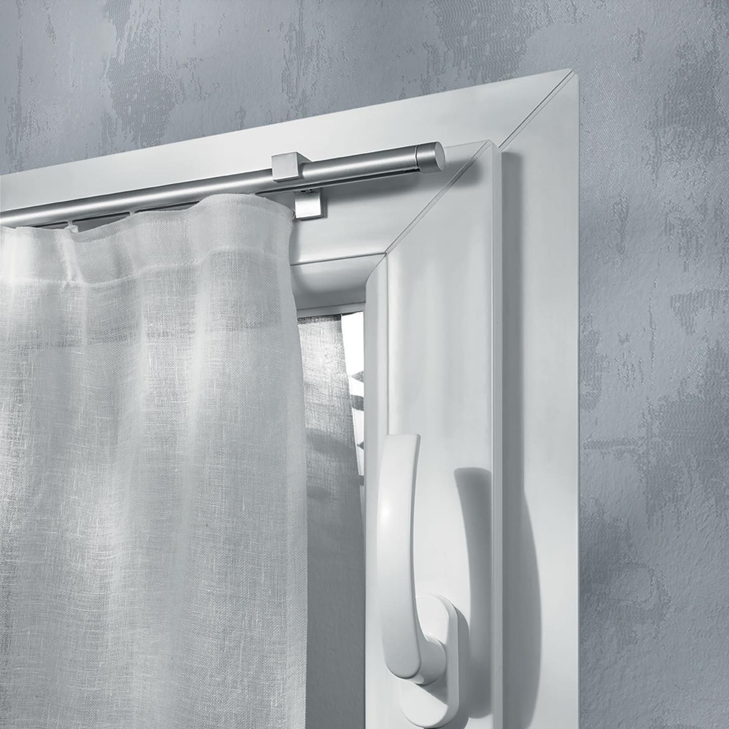 Una tenda bianca è appesa a una cornice bianca della finestra