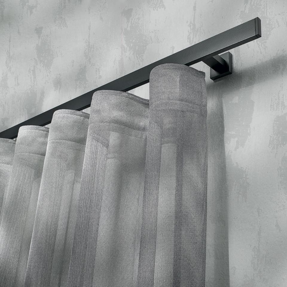 Una tenda grigia è appesa a un bastone per tende nero