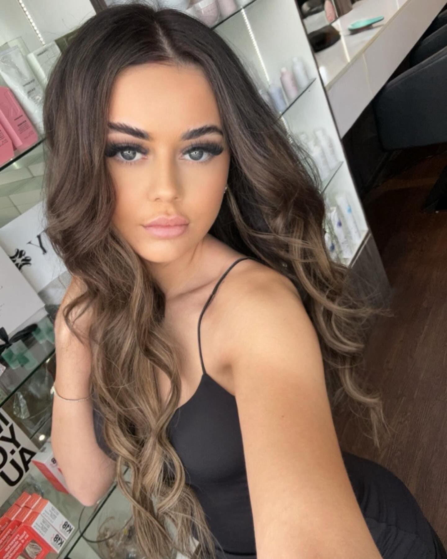 Woman With Wavy Brown Hair, Wearing a Black Top, Posing in a Well-lit Salon — Studio 23 In Biggera Waters, QLD