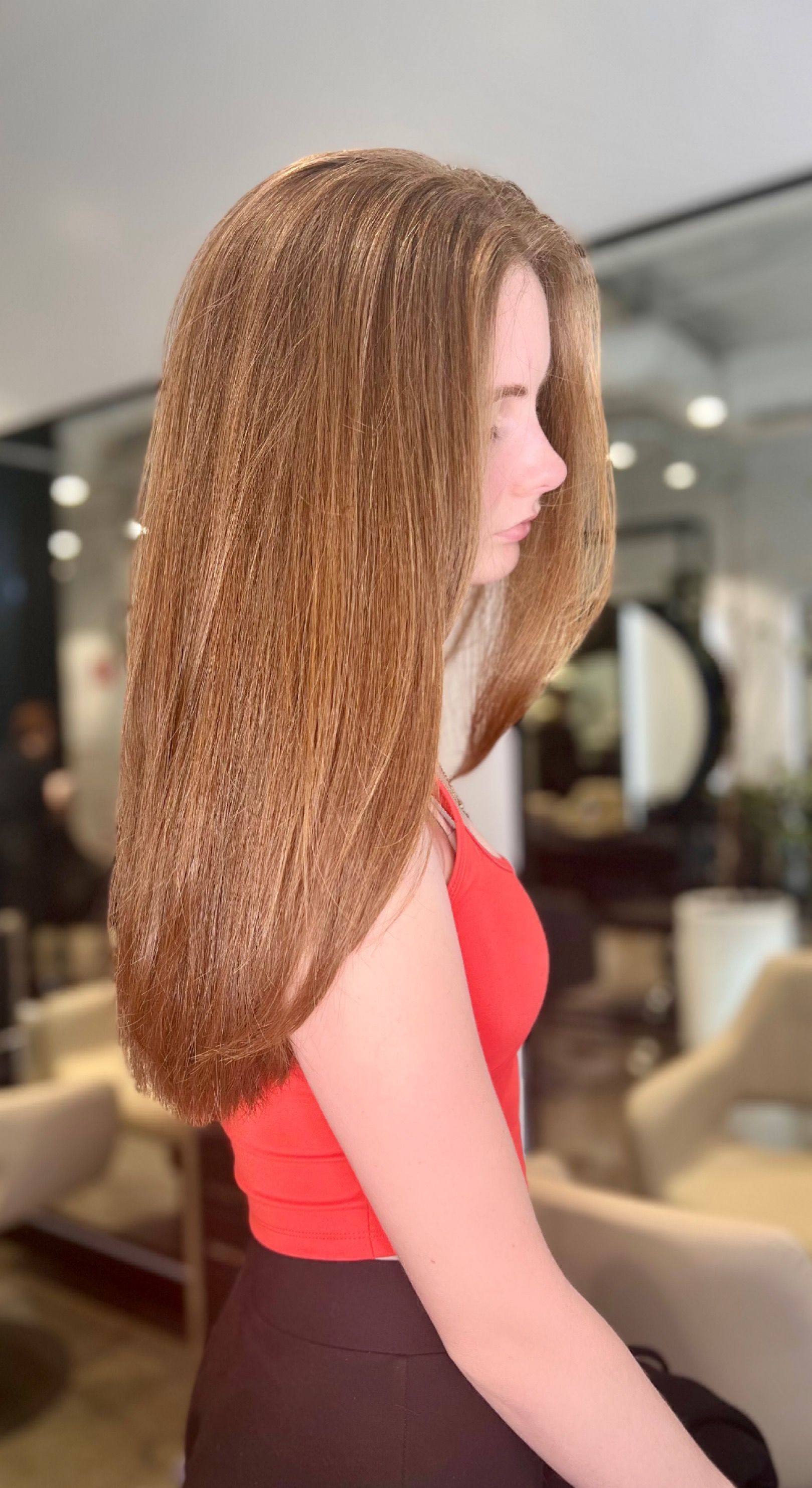 Woman with long brown hair, wearing a red top, stands in a salon — Studio 23 In Biggera Waters, QLD