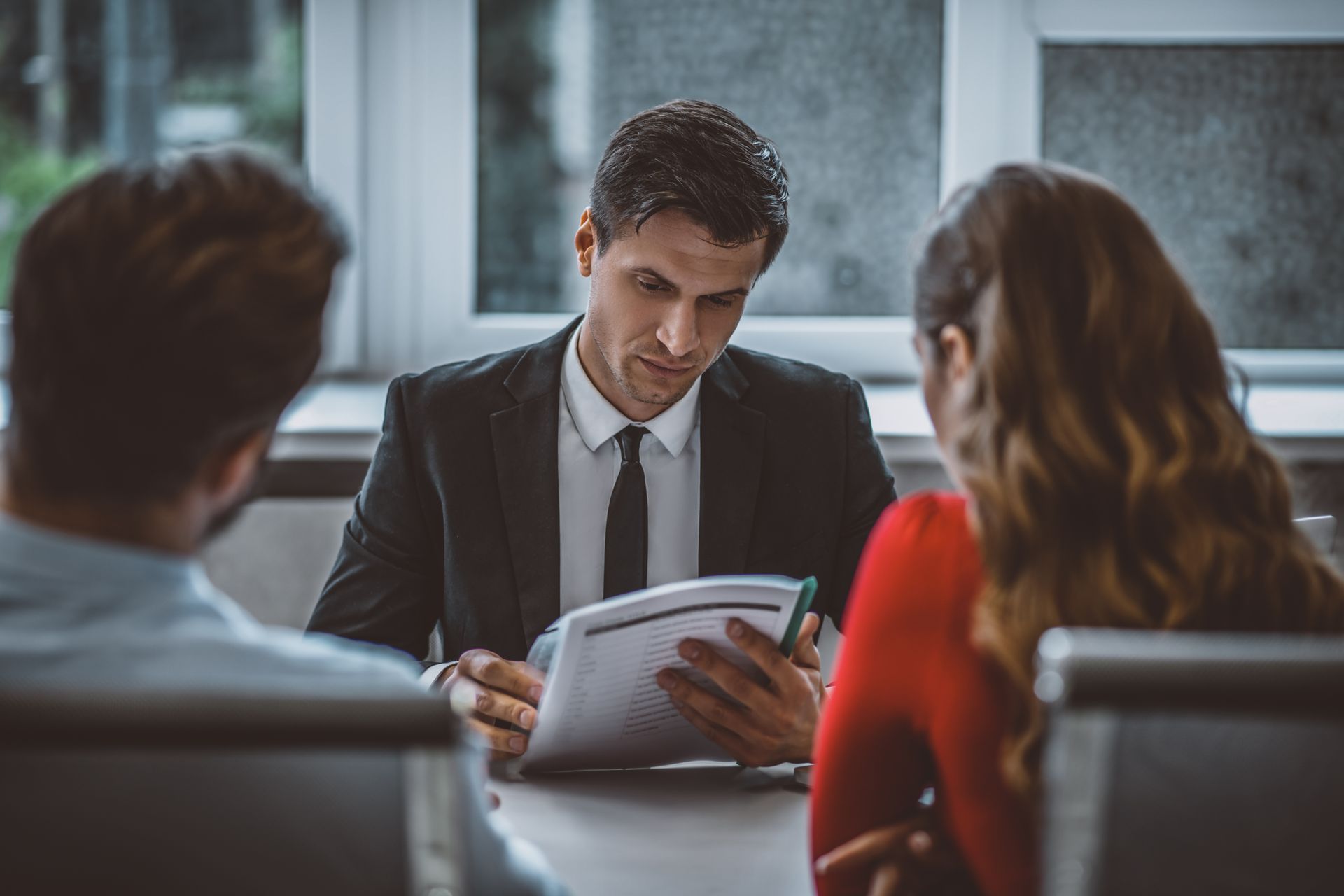 Business meeting with a man reviewing documents while two colleagues sit across the table