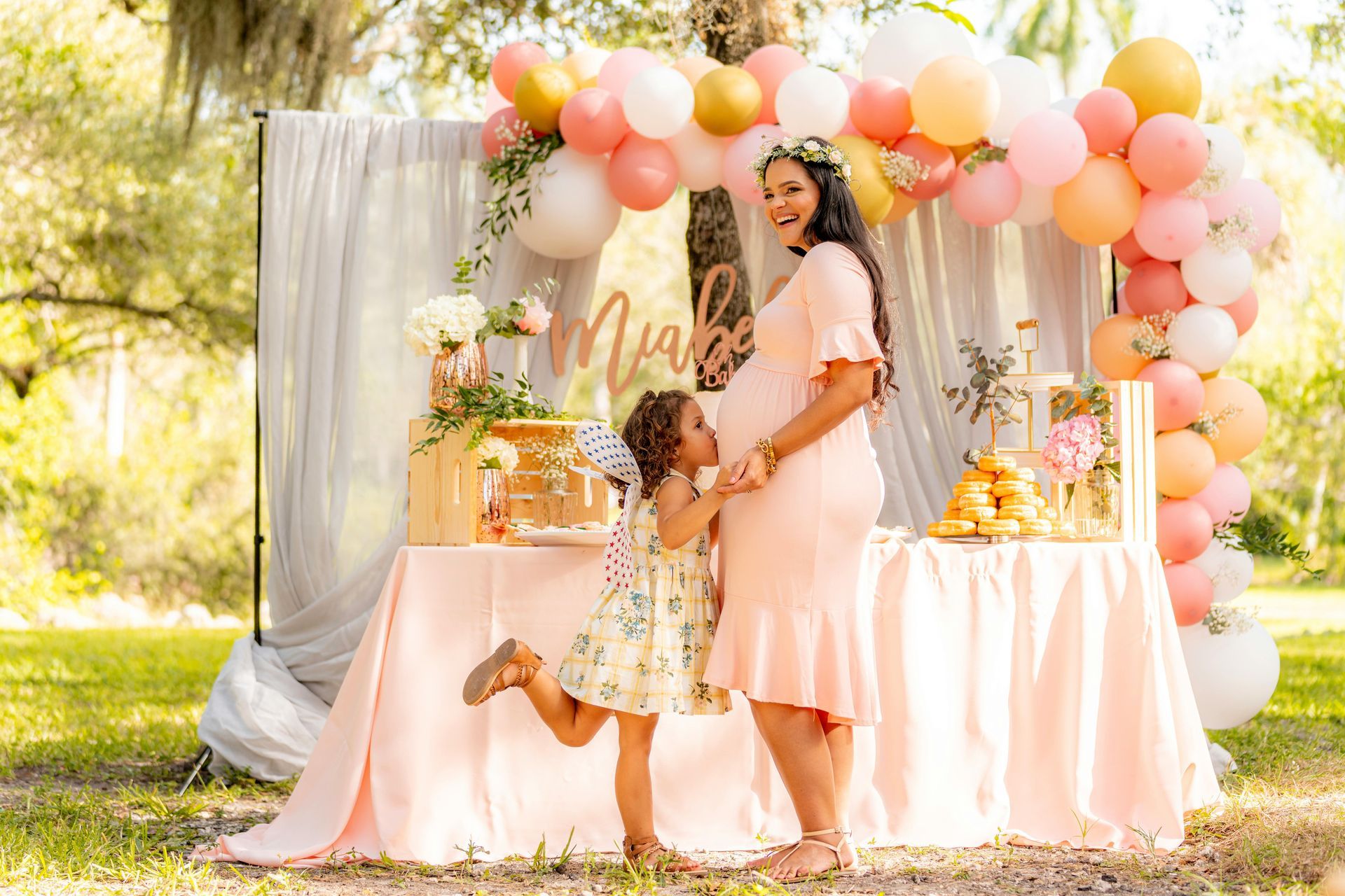 A pregnant woman is standing next to a little girl at a baby shower.