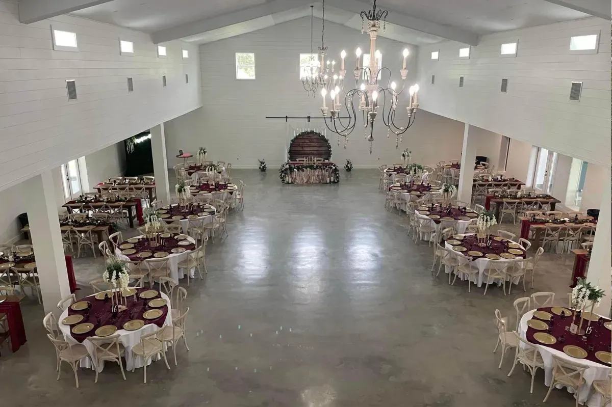 A large room with tables and chairs set up for a wedding reception.