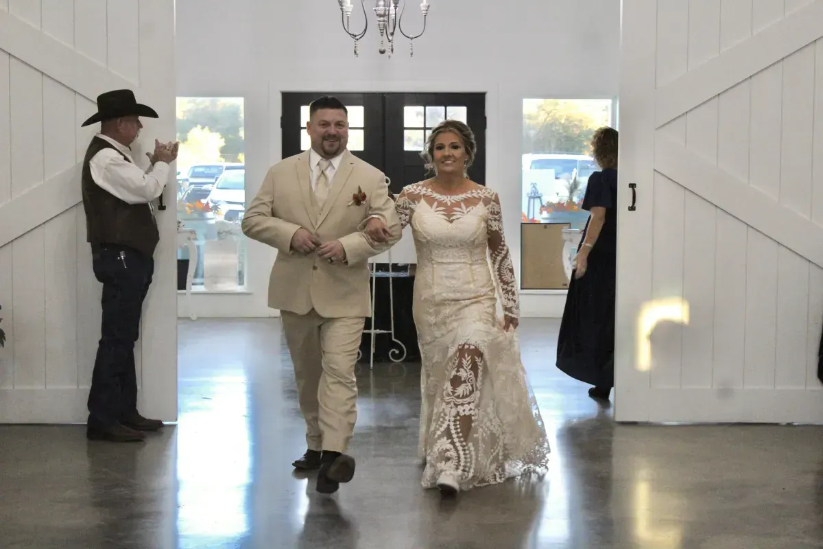 A bride and groom are walking down the aisle at their wedding reception.