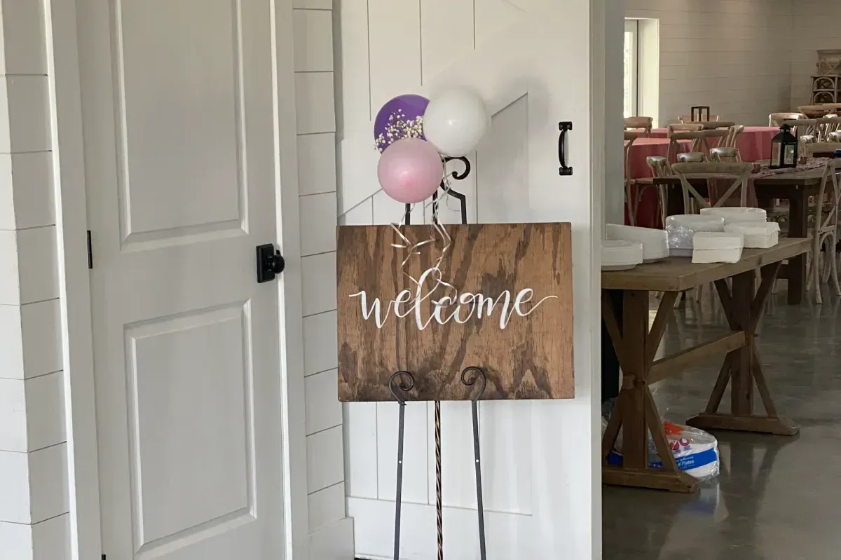 A wooden welcome sign is hanging on a wall next to a door.