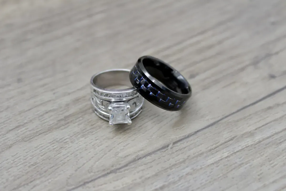 Two wedding rings are sitting on a wooden table.