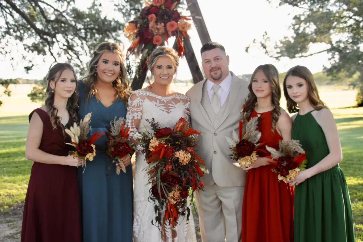 A bride and groom are posing for a picture with their bridesmaids.
