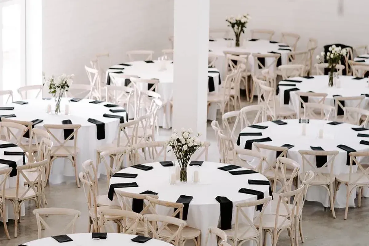 A large room filled with tables and chairs set up for a wedding reception.