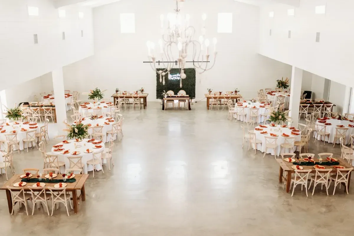 A large room with tables and chairs set up for a wedding reception.