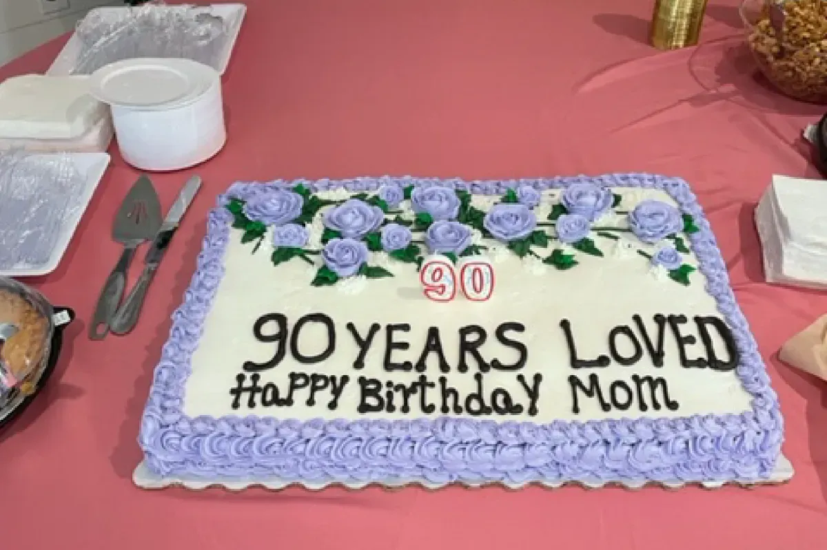 A cake that says 90 years loved happy birthday mom