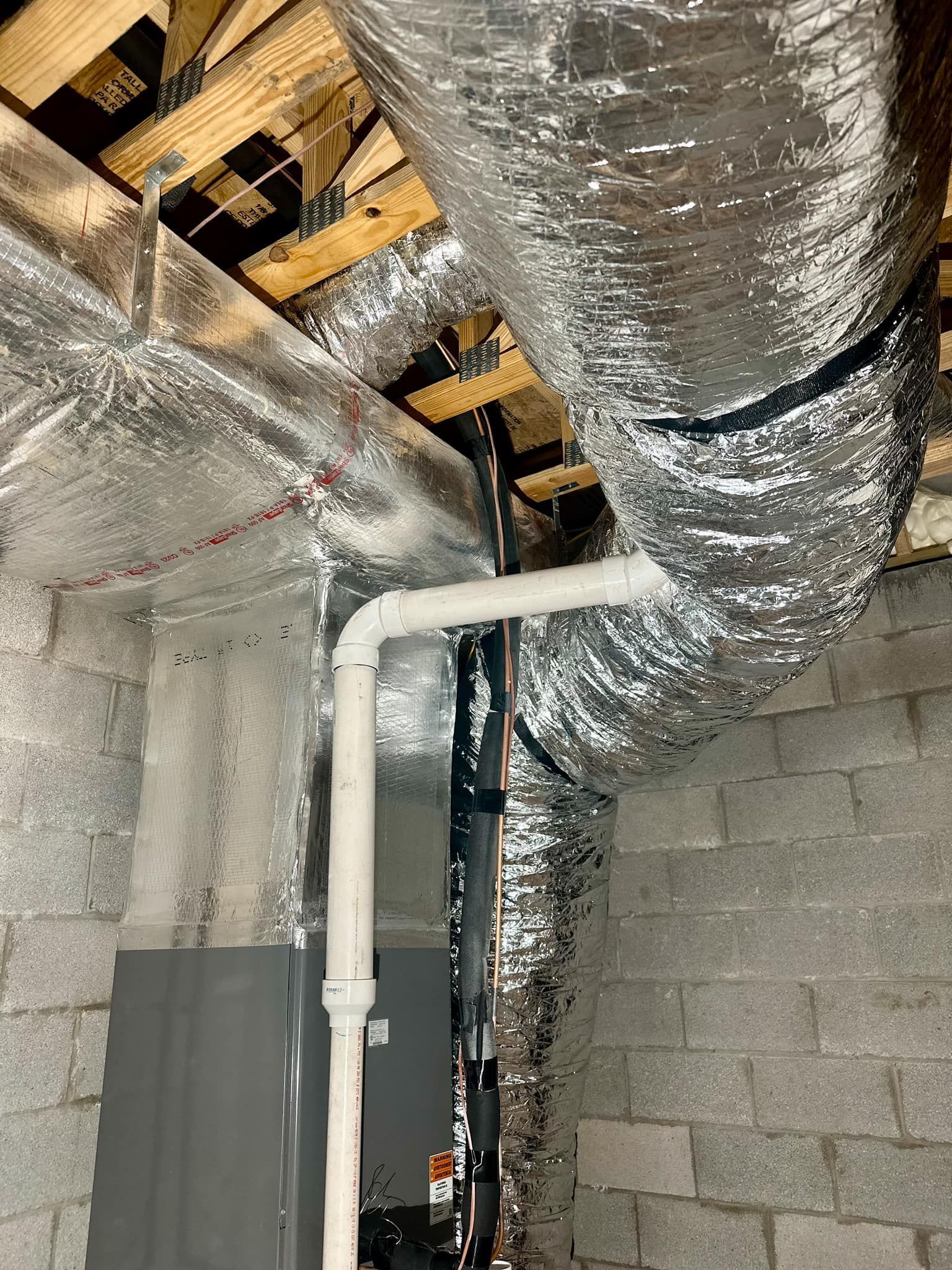 A room with a lot of pipes and aluminum foil on the ceiling.