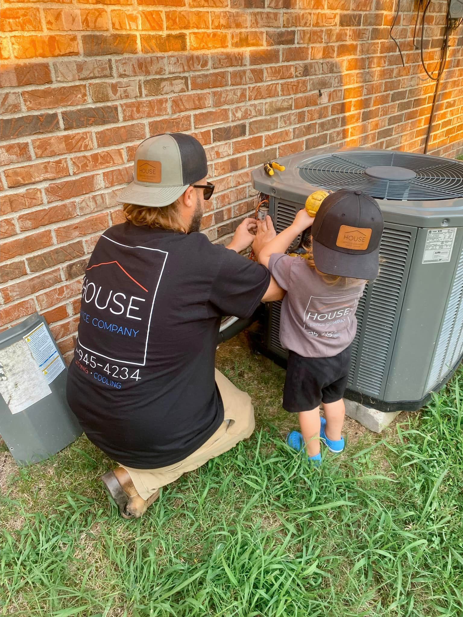 A man and a child are working on an air conditioner.