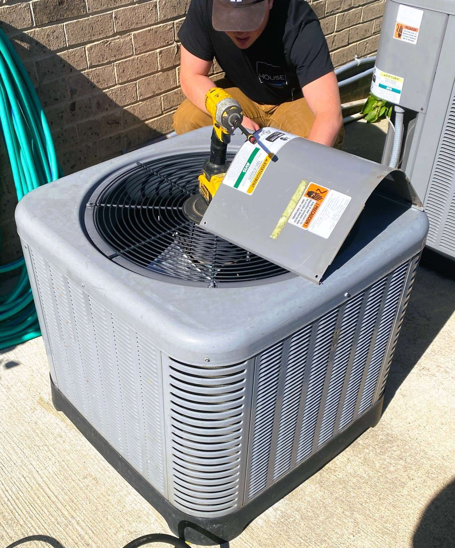 A man is working on an air conditioner with a drill