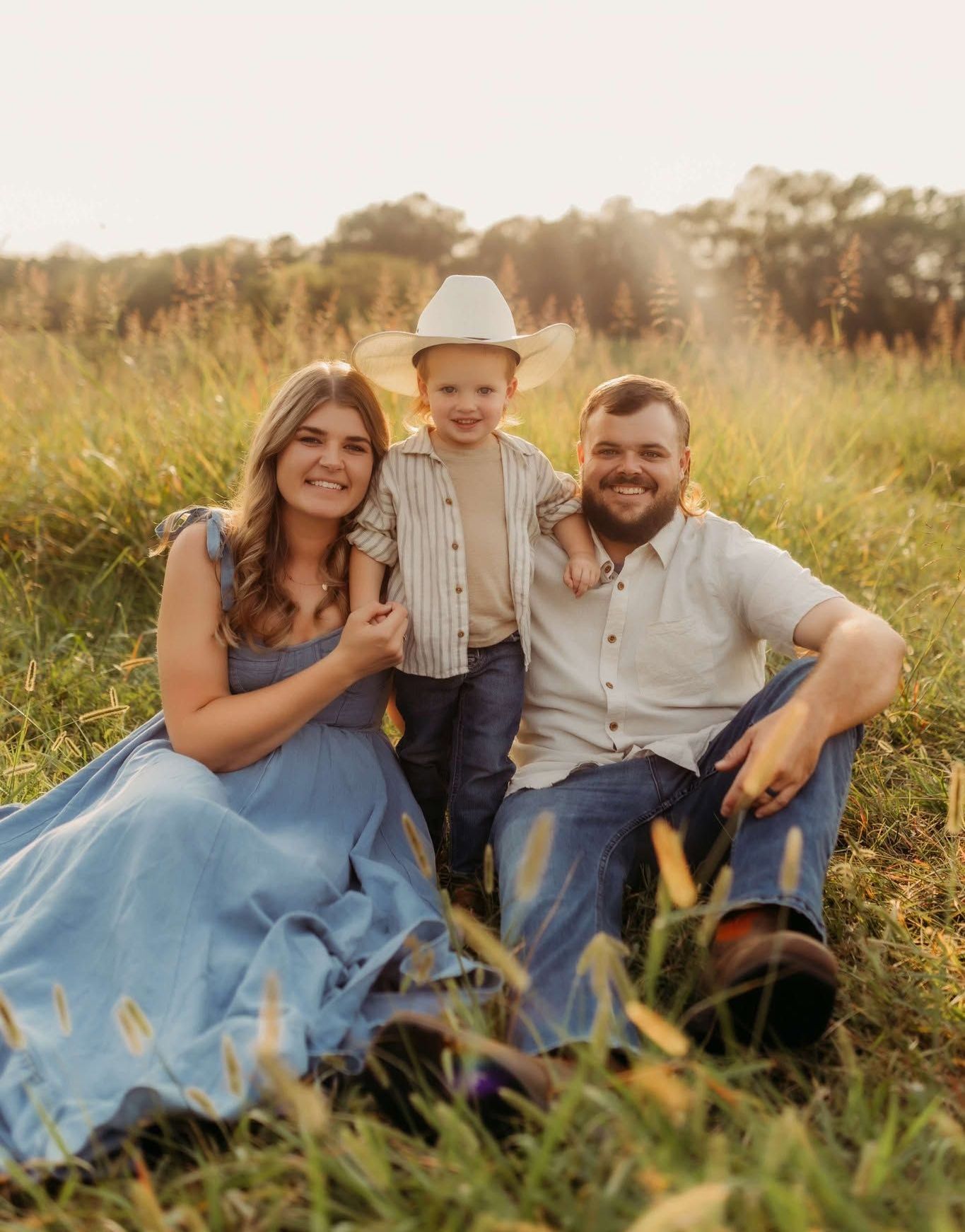 A man , woman and child are posing for a picture in a field.