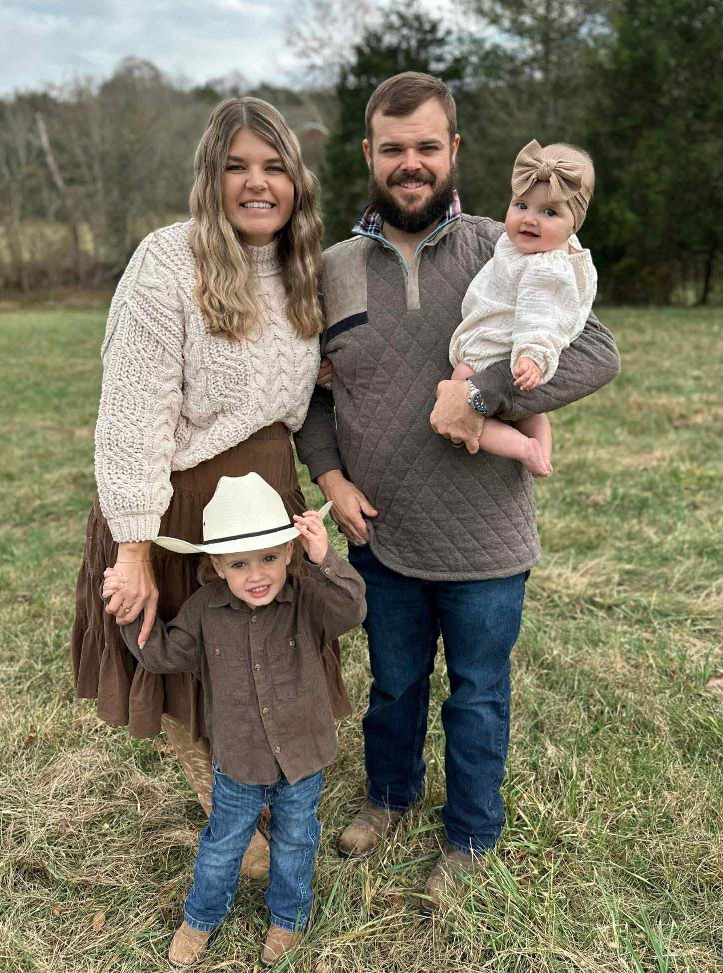 A man , woman and child are posing for a picture in a field.
