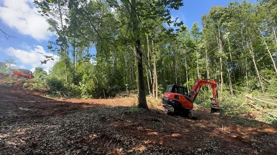 A red excavator is sitting in the middle of a forest.