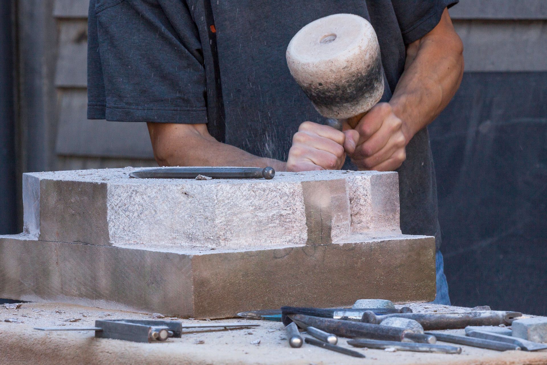 A man is carving a piece of stone with a hammer – Colac, VIC - Bartlett Bros Pty Ltd