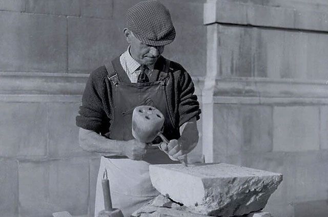 A man is carving a stone with a hammer in a black and white photo – Colac, VIC - Bartlett Bros Pty Ltd