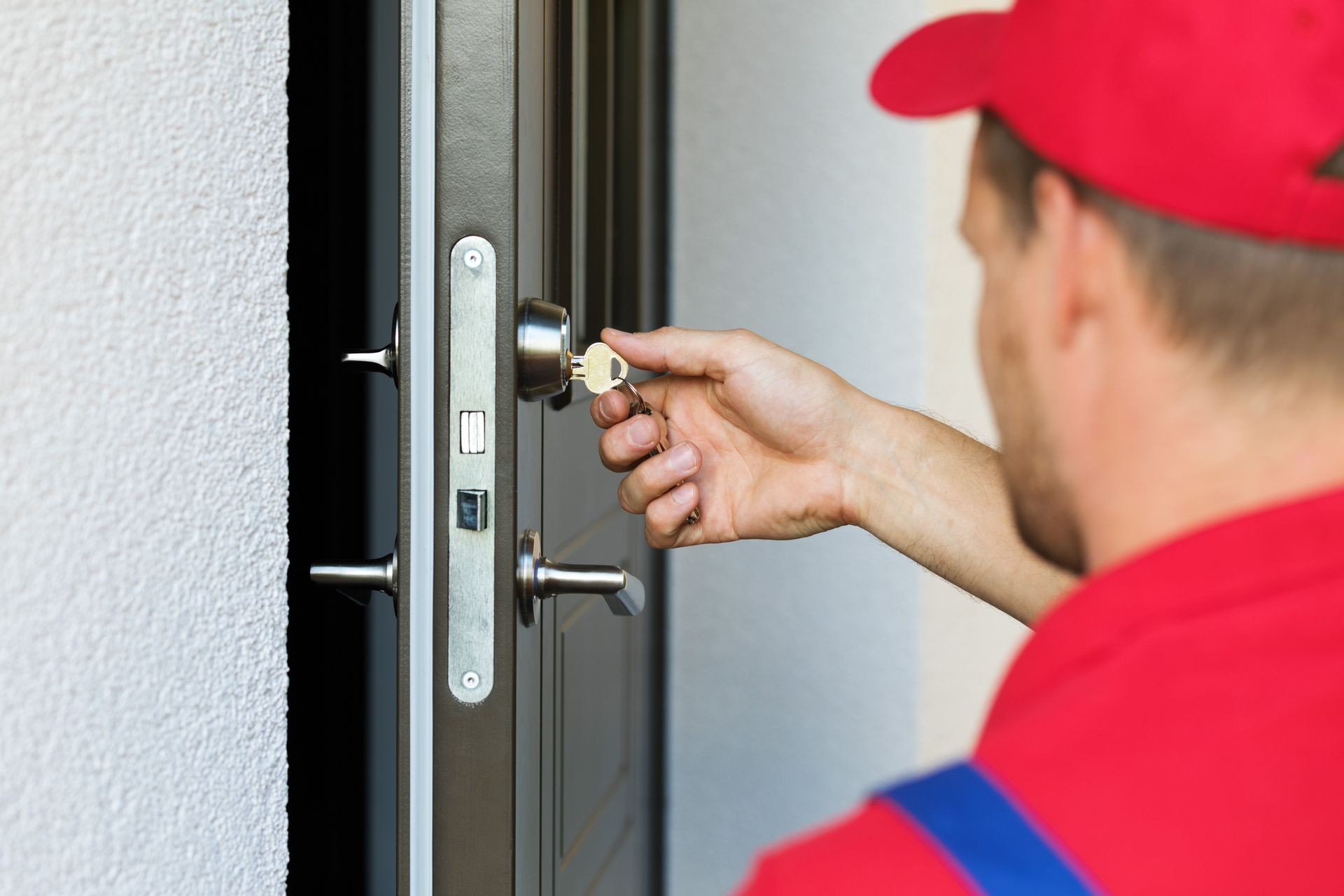 Delivery worker unlocking a front door with a key, wearing a red cap and shirt