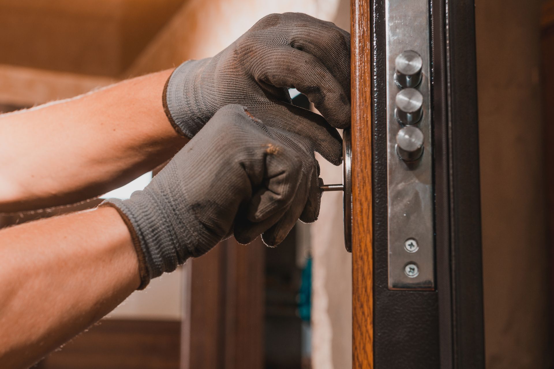 Gloved hands installing a door lock on a wooden door frame