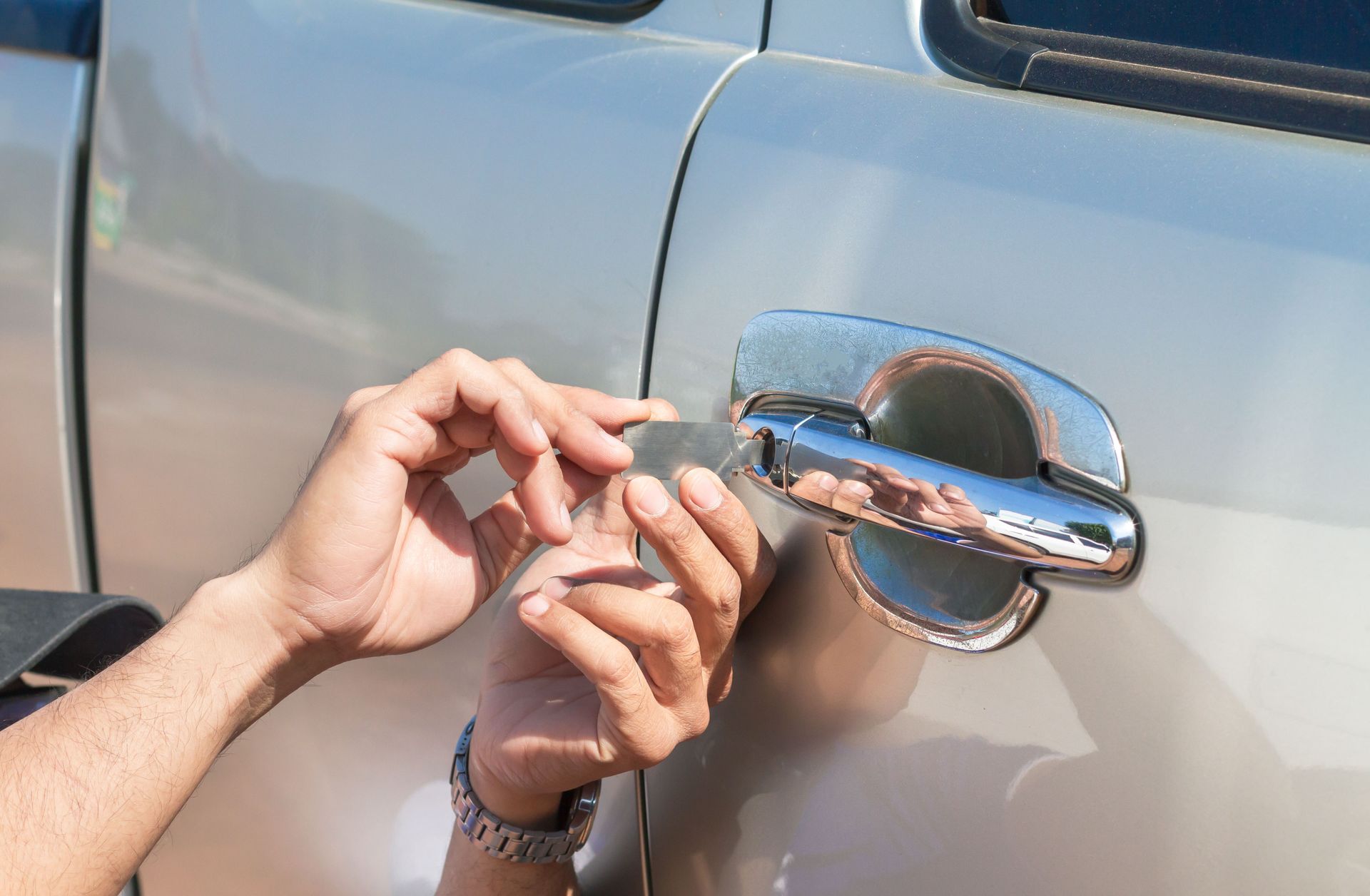 Hands using a key near a silver car door handle to unlock the vehicle