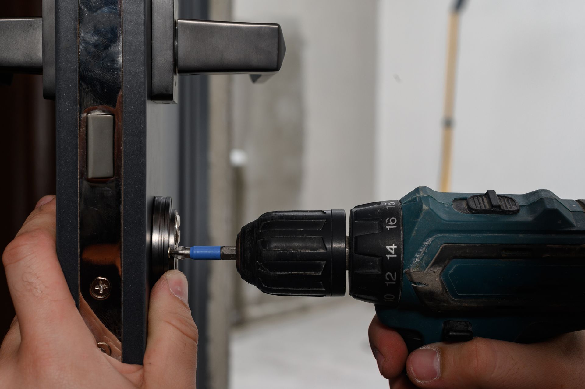 Hand drilling a screw into a metal door lock assembly