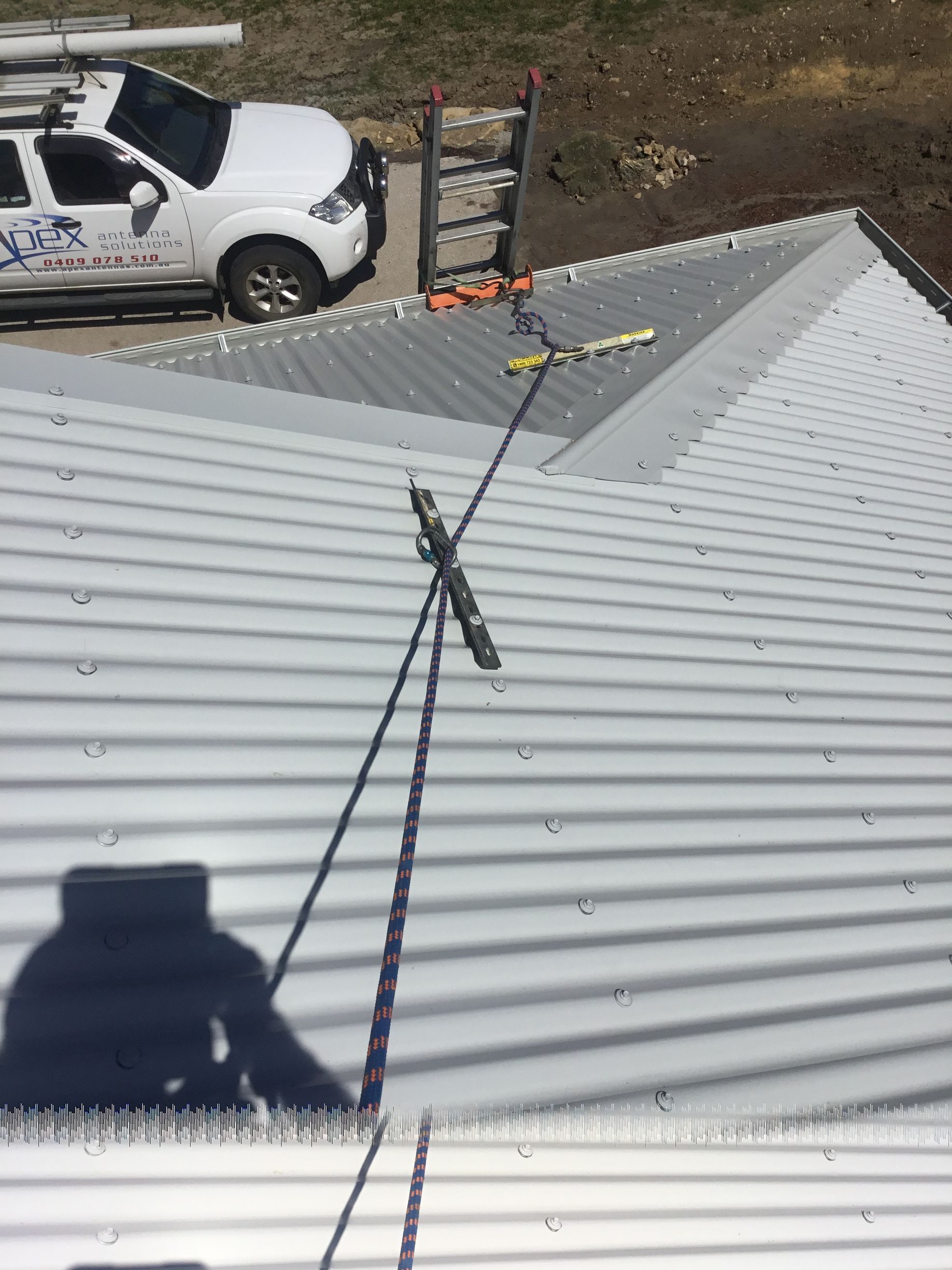 Worker on a Metal Roof With a Safety Line and Antenna — Apex Antenna Solutions Pty Ltd in Whitsundays, QLD
