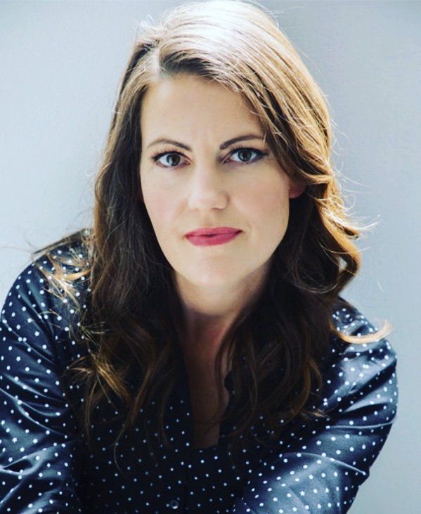 A woman in a polka dot shirt is looking at the camera