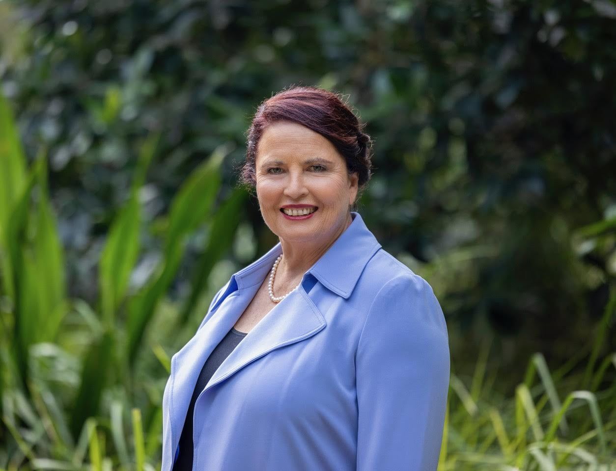 A woman in a blue jacket is smiling for the camera.